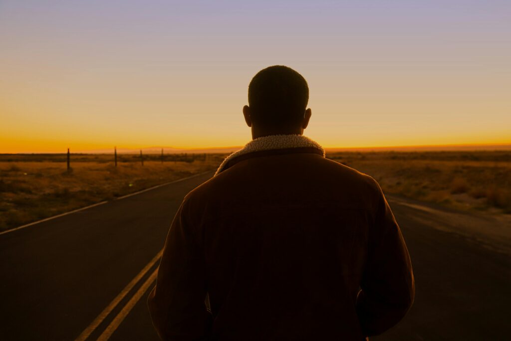 Silhouette of a man in a desert setting during a stunning sunset with warm hues.